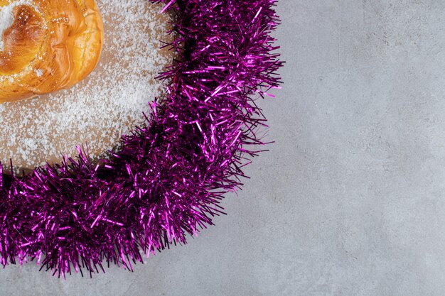 Dessous de guirlande violette avec un petit pain sur une surface en marbre