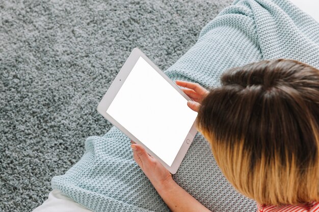 De dessus de femme avec tablette sur le lit