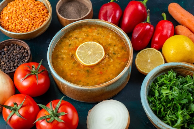 Dessus de près vue délicieuse soupe de légumes avec des légumes verts et des assaisonnements sur le bureau bleu foncé.