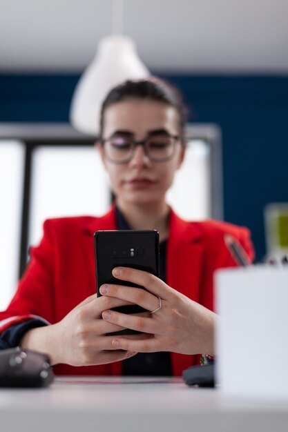 Détail de mise au point sélective sur smartphone pendant que la femme d'affaires envoie des SMS