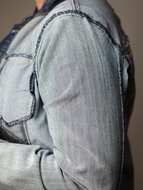 Détails du modèle portant une veste en jean bleu