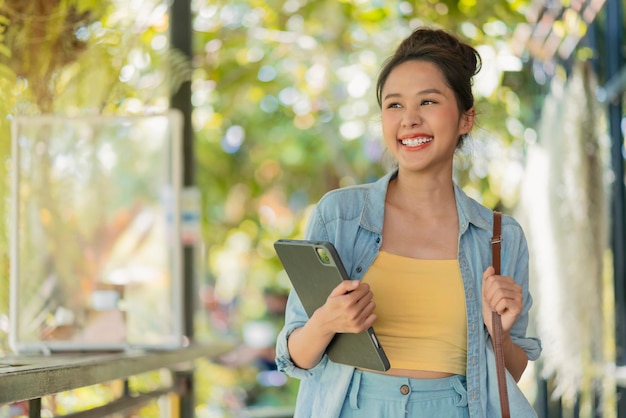 Détendez-vous décontracté insouciant souriant asiatique femme nomade numérique programmeur indépendant main tenir un ordinateur portable marchant à la plage et cocotier bleu ciel nouveau style de vie millénaire travaillant n'importe où avec bonheur