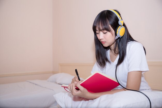 Détendue jeune femme en pyjama écrit un journal sur son lit