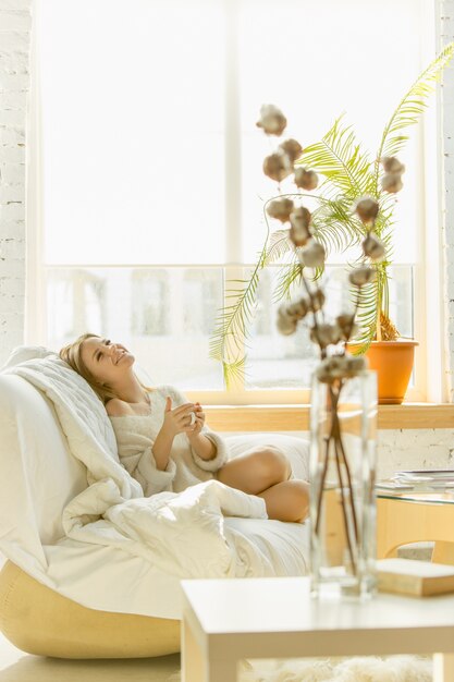 Détente à la maison. Belle jeune femme allongée sur un canapé avec un soleil chaud.