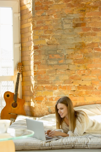 Détente à la maison. Belle jeune femme allongée sur un matelas avec un soleil chaud. Une mannequin blonde caucasienne a le temps de se reposer le week-end