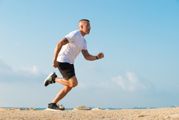 Déterminé jeune athlète courir sur la plage