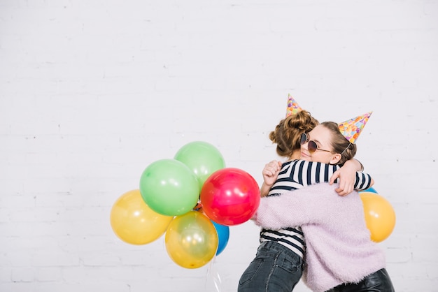 Deux, adolescentes, tenue, ballons, dans main, embrasser, autre, contre, toile de fond blanc