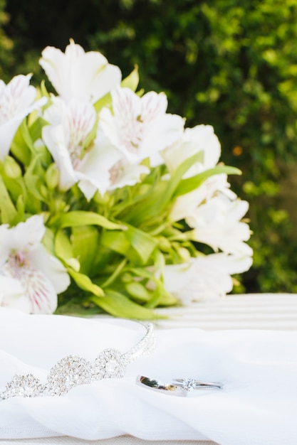 Deux alliances et couronne sur foulard avec bouquet de fleurs magnifique sur la table