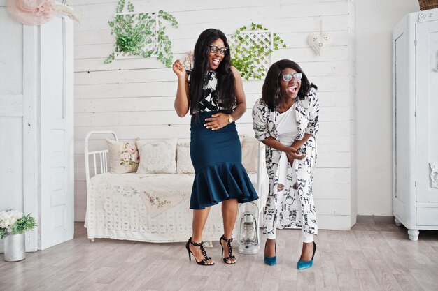 Deux amies africaines portent des lunettes posées à l'intérieur de la salle blanche Rire et s'amuser ensemble