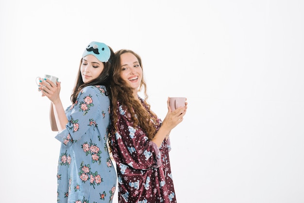 Deux amies debout dos à dos tenant une tasse de café