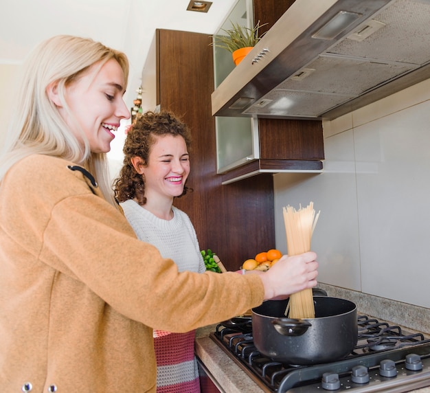 Deux amies faisant cuire des spaghettis dans la casserole