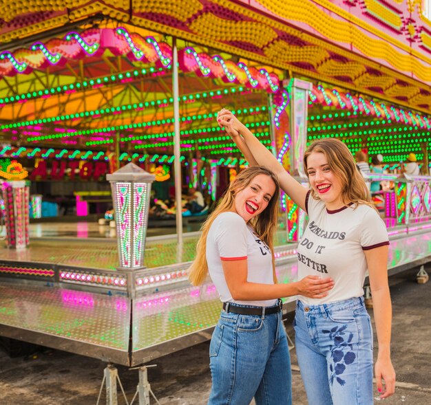 Deux amies heureux levant les bras au parc d&#39;attractions