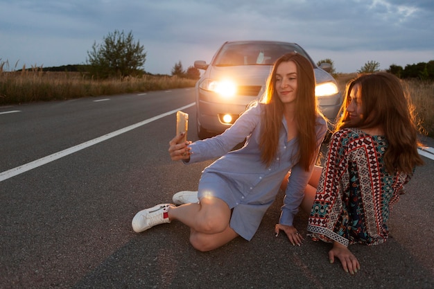 Deux Amies Prenant Un Selfie Devant La Voiture Sur La Route