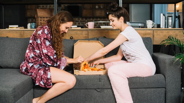 Photo gratuite deux amies prenant des tranches de pizza dans une boîte