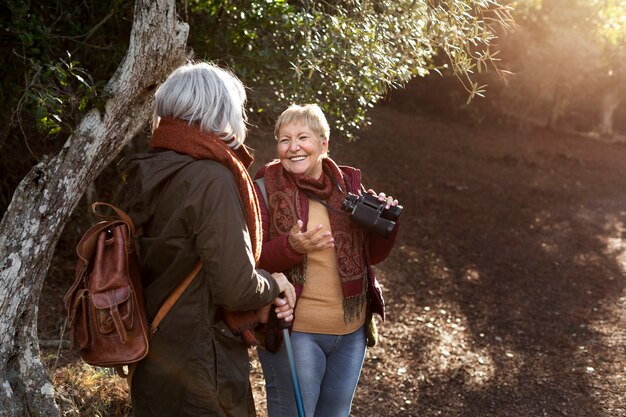 Deux amies seniors profitant d'une randonnée dans la nature tout en utilisant des jumelles