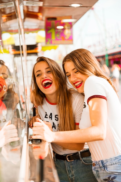 Deux amies souriantes s&#39;amusant au parc d&#39;attractions