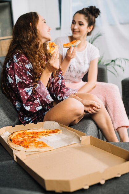 Deux amies avec une tranche de pizza se regardent