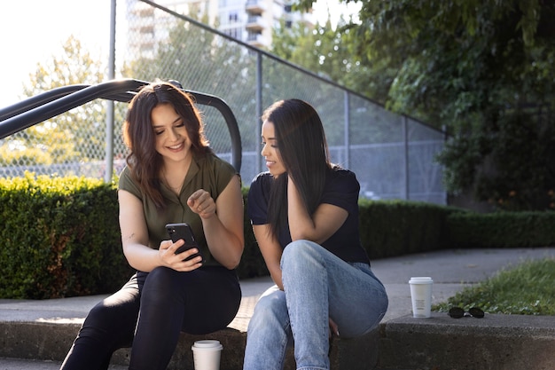 Deux amies utilisant un smartphone dans le parc