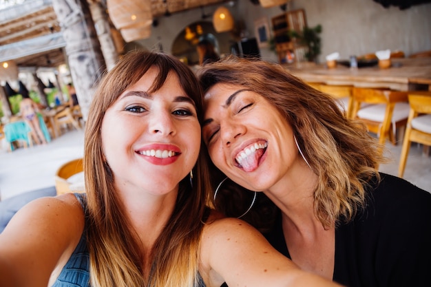 Deux amis de femme de race blanche européenne avec maquillage naturel et cheveux courts prennent selfie au café d'été