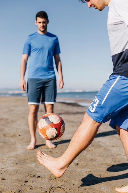 Deux amis jouant au football à la plage