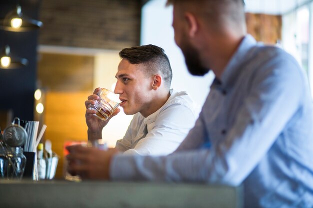 Deux amis masculins assis au comptoir du bar en appréciant les boissons