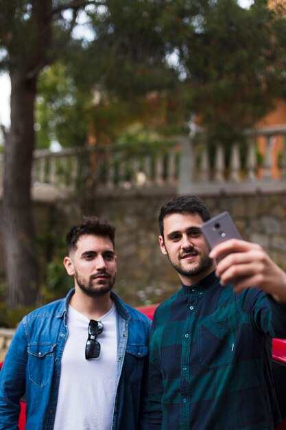 Deux amis masculins prenant selfie sur téléphone mobile