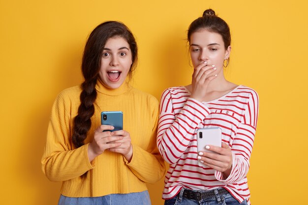 Deux amis avec des téléphones lisant des nouvelles choquantes sur le réseau social