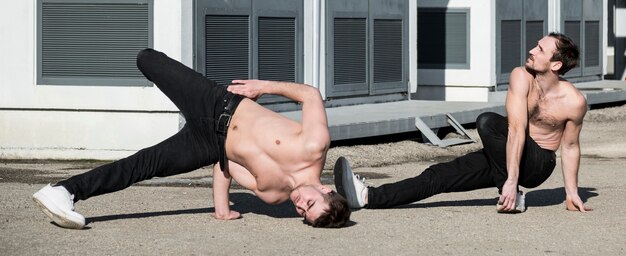 Deux artistes hip hop torse nu pratiquant la routine de danse à l'extérieur