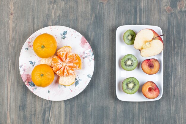 Deux assiettes de divers fruits sur une surface en bois