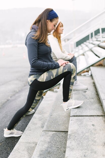 Deux athlètes féminines s&#39;étendant la jambe sur les marches