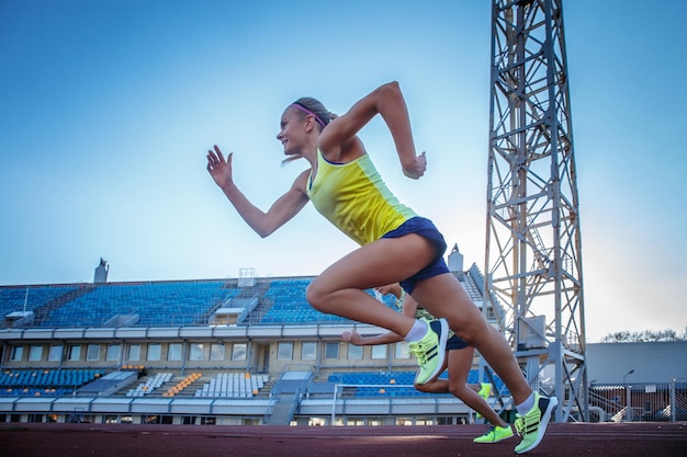 Deux athlètes féminines sprinter courant sur la course de tapis roulant pendant l'entraînement dans le stade d'athlétisme.