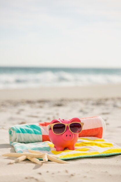 Deux banques étoiles de mer et tirelire avec des lunettes de soleil sur la plage de couverture