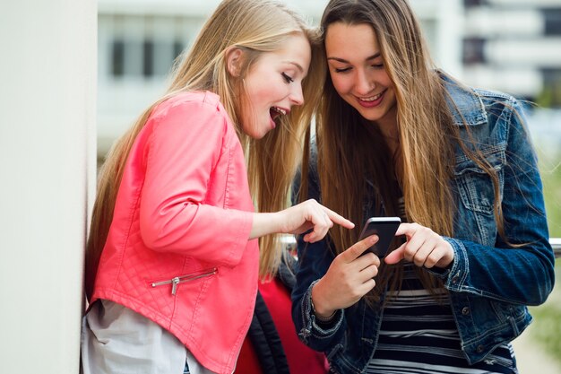 Deux beaux étudiants utilisant un téléphone mobile dans la rue.