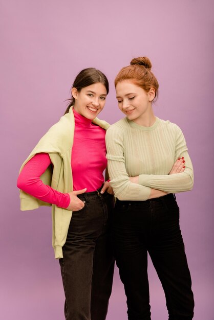 Deux belles jeunes femmes caucasiennes brune et rousse dans des vêtements d'automne décontractés sur fond violet Style de vie différentes émotions concept de loisirs