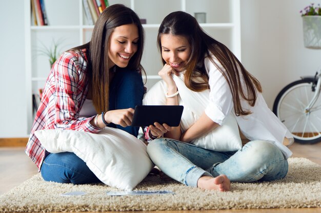 Deux belles jeunes femmes utilisant la tablette numérique à la maison.