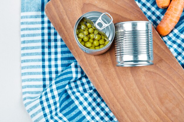 Deux boîtes de pois verts bouillis, légumes et nappe.