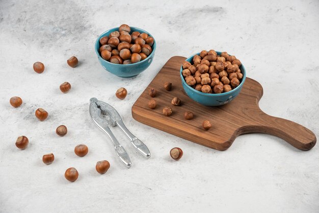 Deux bols bleus de noisettes décortiquées et de noyaux sur une table en marbre.