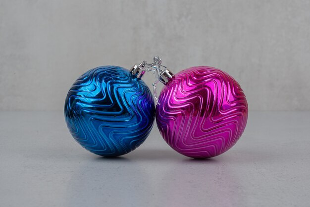Deux boules de Noël colorées sur mur gris.