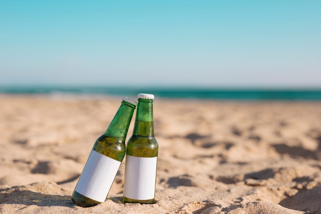 Deux bouteilles de bière sur la plage de sable fin