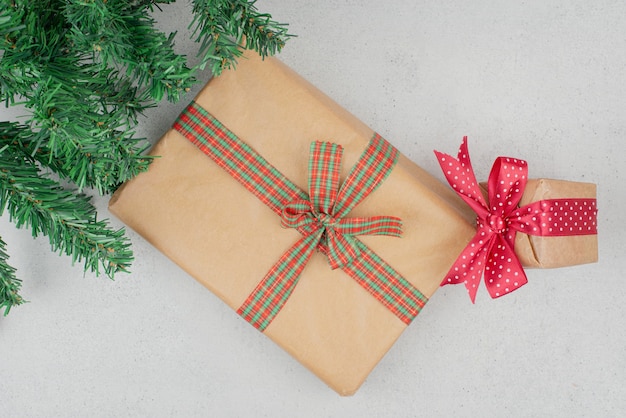 Photo gratuite deux coffrets cadeaux mignons avec des guirlandes vertes sur une surface grise.