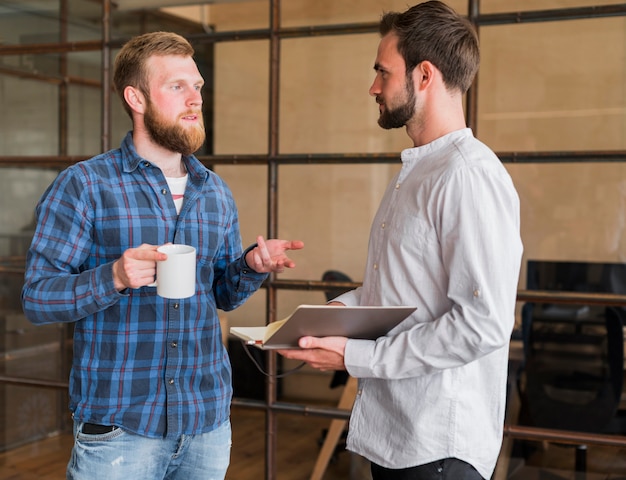 Deux collègues masculins discutant entre eux sur le lieu de travail