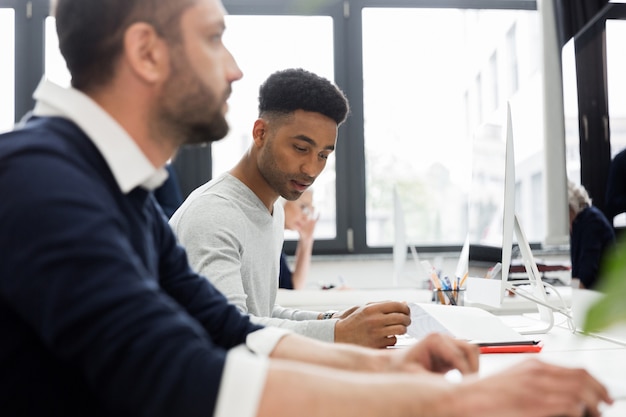 Deux collègues masculins travaillant à l'ordinateur dans un bureau