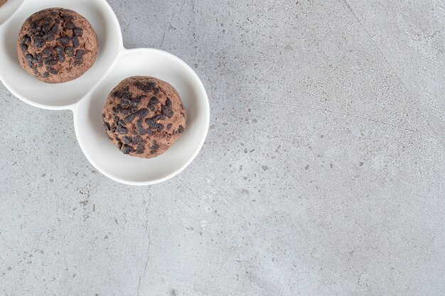 Deux cookies aux pépites de chocolat sur un plateau sur une surface en marbre