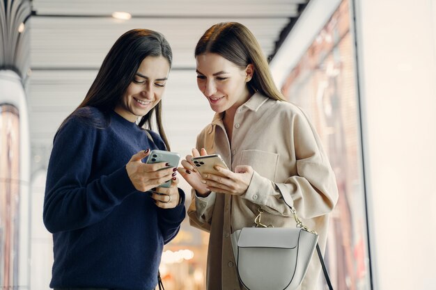 Deux copines utilisent leur téléphone portable tout en explorant une nouvelle ville la nuit