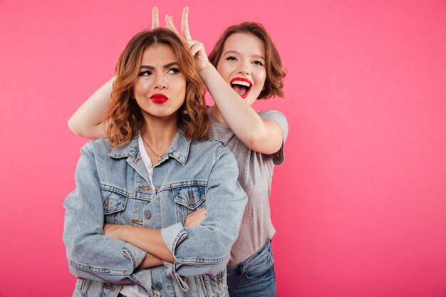 Deux dames amis debout isolés s'amusent.