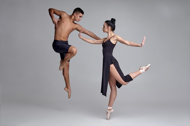 Deux danseurs de ballet modernes athlétiques posent sur un fond de studio gris