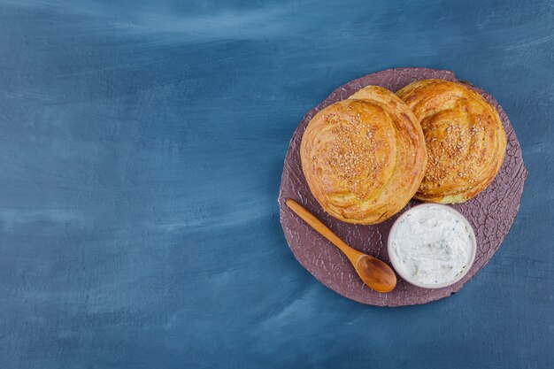 Deux délicieuses pâtisseries traditionnelles et crème sure sur morceau de bois.