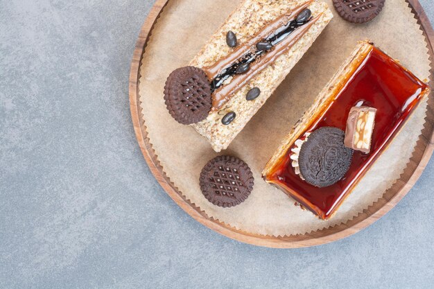 Deux délicieux morceaux de gâteaux avec des biscuits sur planche de bois