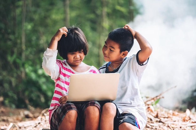 Deux enfants asiatiques se demandent quand étudier via un ordinateur portable à la maison elearning école à distance dans l'arrière-pays