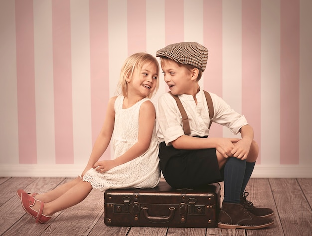 Deux enfants assis sur la valise en bois